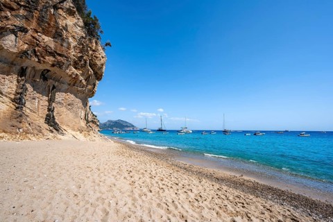 Sandy beach beach and steep cliffs at Cala Luna, Golfo di Orosei, Baunei, Sardinia, Italy