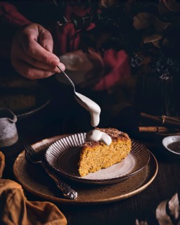 A delightful slice of pumpkin and cinnamon sponge cake, topped with a generous drizzle of creamy