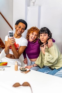 Gay man and lesbian couple taking selfie while making up at home