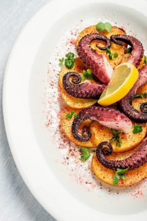 Octopus with potatoes and spices, on a light plate, top view, no people, homemade, close-up