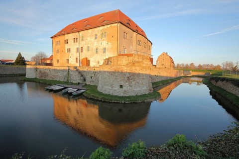 Renaissance moated castle with pond and reflection, fortress with bulwark, lighting atmosphere,
