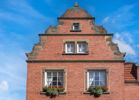 Traditional brick building with windows and flowers against a clear blue sky, Münsterland, North