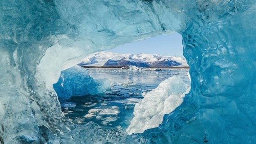 Stunning view from within a crystal-blue ice cave in Jokulsarlon, Iceland, framing the glacier