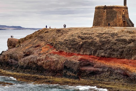 Historic fortress perched on rocks above the sea with views of the coast and the neighboring island