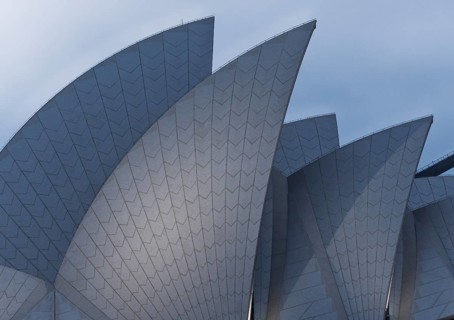 Close up of a Sidney Opera House known for its unique sail like roof design. The structure features