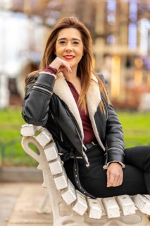 Stylish woman sitting on a park bench, savoring the vibrant urban scenery while enjoying a relaxed