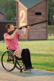 An old man in a wheelchair trains in a shooting range, aiming with precision and focus