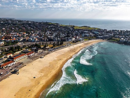 Aerial view of a beautiful coastal town with sandy beach, blue ocean, and residential area in