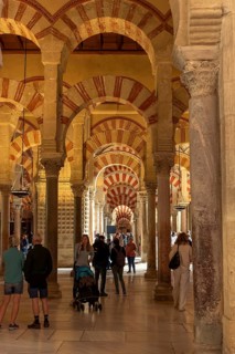 Architecture with columns and decorative arches, people walking around, Cathedral Mosque of Cordoba