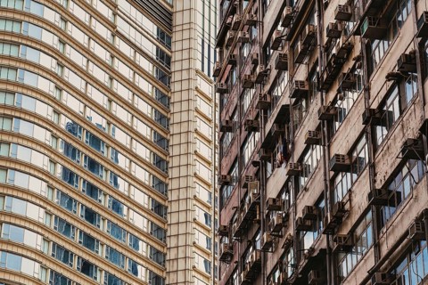 This image captures a striking contrast between sleek, modern architecture and an old residential