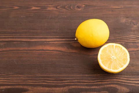 Yellow Lemon Cut in half on brown wooden background. Side view, copy space. healthy food,