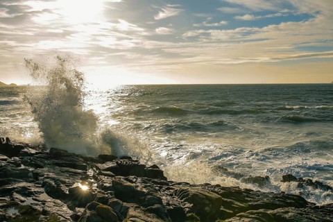 Capturing the dynamic moment of ocean waves dramatically crashing against rugged coastal rocks,