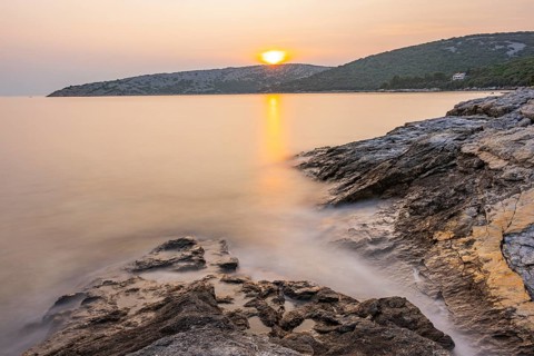 Sunset over crystal clear water on the beach of Ustrine Bay on the island of Cres, long exposure,