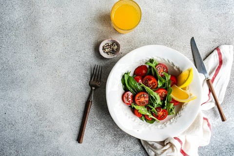 Fresh arugula and herb salad garnished with Himalayan salt, cherry tomatoes, and mixed seeds,