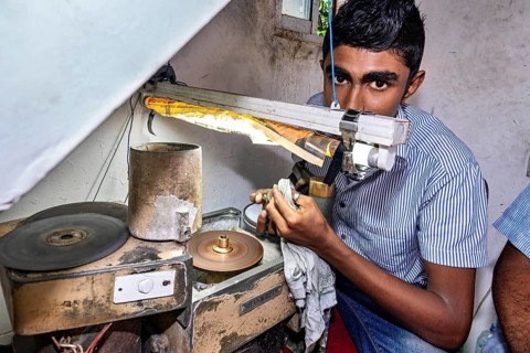 Young man working concentratedly with a machine under a work lamp, The gemstone cutters in the city