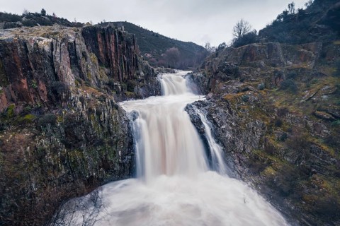 Majestic view of the cascading waters at Cascada del Aljibe, set amidst rugged cliffs and lush