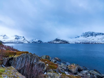 View across the fjord to snowy mountains, Husøy, Senja island, Troms, Norway