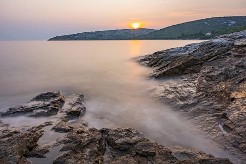 Sunset over crystal clear water on the beach of Ustrine Bay on the island of Cres, long exposure,