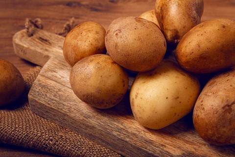 Raw potatoes, scattered on a chopping board, close-up, no people