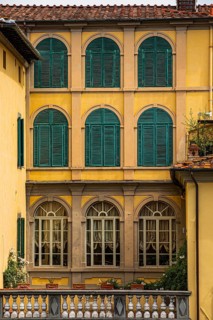 Arched windows with green shutters in a pastel-coloured façade, historic city centre, Lucca,