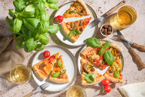 Slices of homemade vegetarian pizza with vibrant toppings of zucchini, eggplant, and olives,