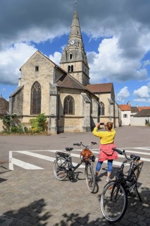 Cyclist taking photos in front of the church Église Saint-Cassien, Savigny-lès-Beaune, Département
