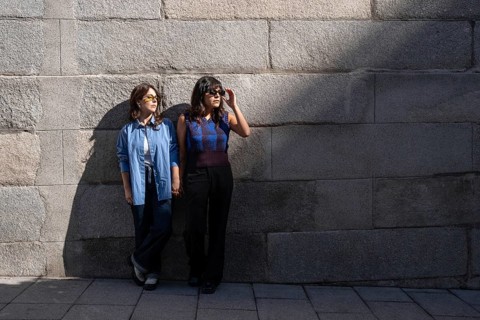 An urban setting with a multiethnic lesbian couple holding hands, showcasing diversity and love.