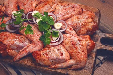 Chicken wings, marinated and laid out on a wooden platter, ready for cooking, grilling or baking,