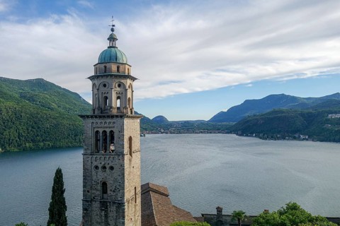 A picturesque scene at Lake Lugano in Ticino, Switzerland, featuring a majestic historic church