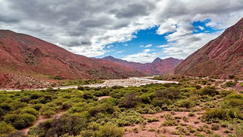 Red mountain landscape, vegetation and a cloudy sky, the landscape and colorful rock formations of