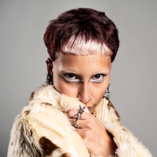 A striking portrait showcasing a woman in a fur coat with unique accessories. The edgy hairstyle