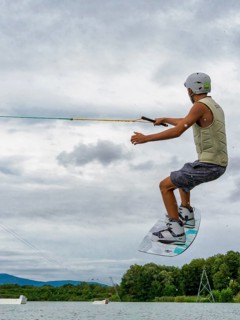 Young man jumping with wakeboard, water sports, water skiing in wakepark