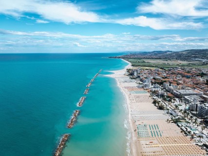 Stunning aerial photo of San Beneddetto, Italy, showcasing a vibrant blue sea meeting sandy beaches