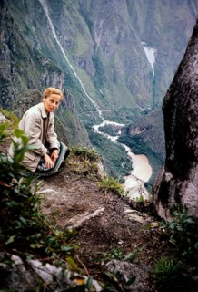Female tourist sitting on the mountain Huayna Picchu overlooking a river gorge, Peru, South America