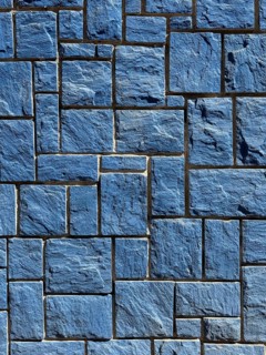 A detailed image of a blue stone wall featuring interlocking rectangular tiles with a rough texture