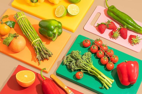 A vibrant assortment of fresh fruits and vegetables on multicolored cutting boards. Includes