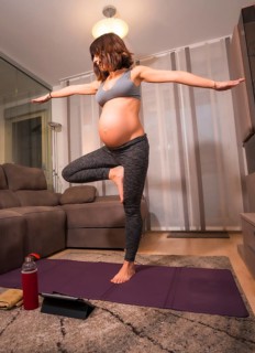 A young pregnant Caucasian woman doing pilates exercise at home in the living room. Online