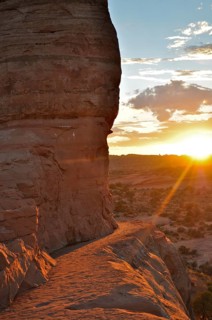 A hiking trail on a rock face near Delicate Arch at sunset in a desert landscape, Arches National