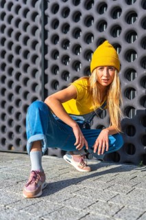 Young woman wearing a yellow beanie, yellow t shirt, and denim overalls, showcasing her urban dance