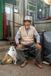 Man with traditional clothes shopping, market stall, Uzgen Bazaar, Ösgön, Osh region, Kyrgyzstan