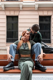 A Colombian lesbian couple sits closely on a bench outdoors, radiating love and acceptance. Their