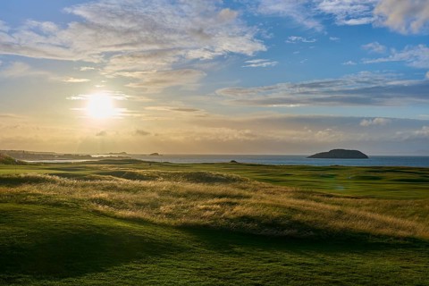 Green field in warm sunset with view of ocean and island, golf course, North Berwick, East Lothian,
