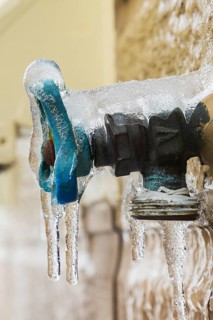 Close-up of outdoor utility brass water faucet with blue handle mounted through Canexel siding on