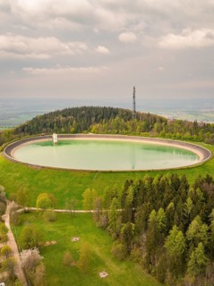 A round water reservoir in the middle of a green forest under a cloudy sky, Sindelfingen, Böblingen