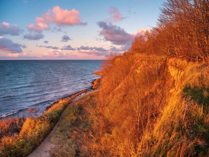 Natural coastal landscape on the Baltic Sea in the last evening light, glowing pink clouds, view of