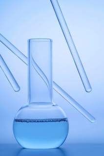 Close-up of a laboratory beaker filled with blue liquid, surrounded by transparent glass rods