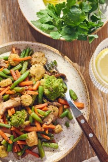 Plate of stir-fried mixed vegetables with green beans, carrots, baby corn, romanesco and mushrooms