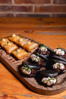 Elegant serving of black octopus bao buns topped with creamy sauce and microgreens, paired with