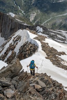 Mountaineer on a rocky ridge with snow, descent from the summit of the Schönbichler Horn, Berliner