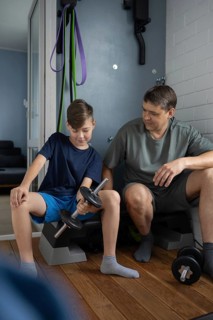 Father and son bonding during a home workout session. The father guides and encourages his son as